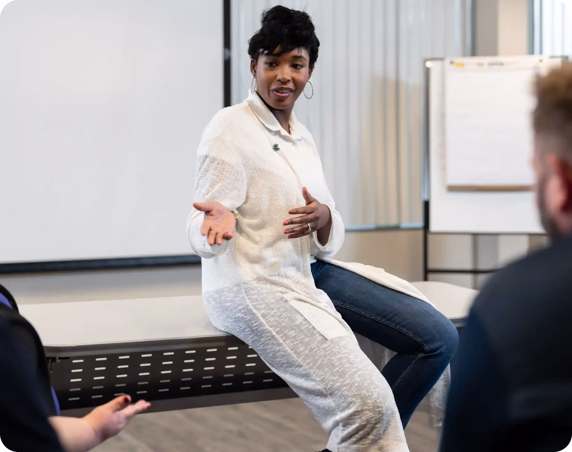 A woman sitting on a desk explaining financial wellness to students