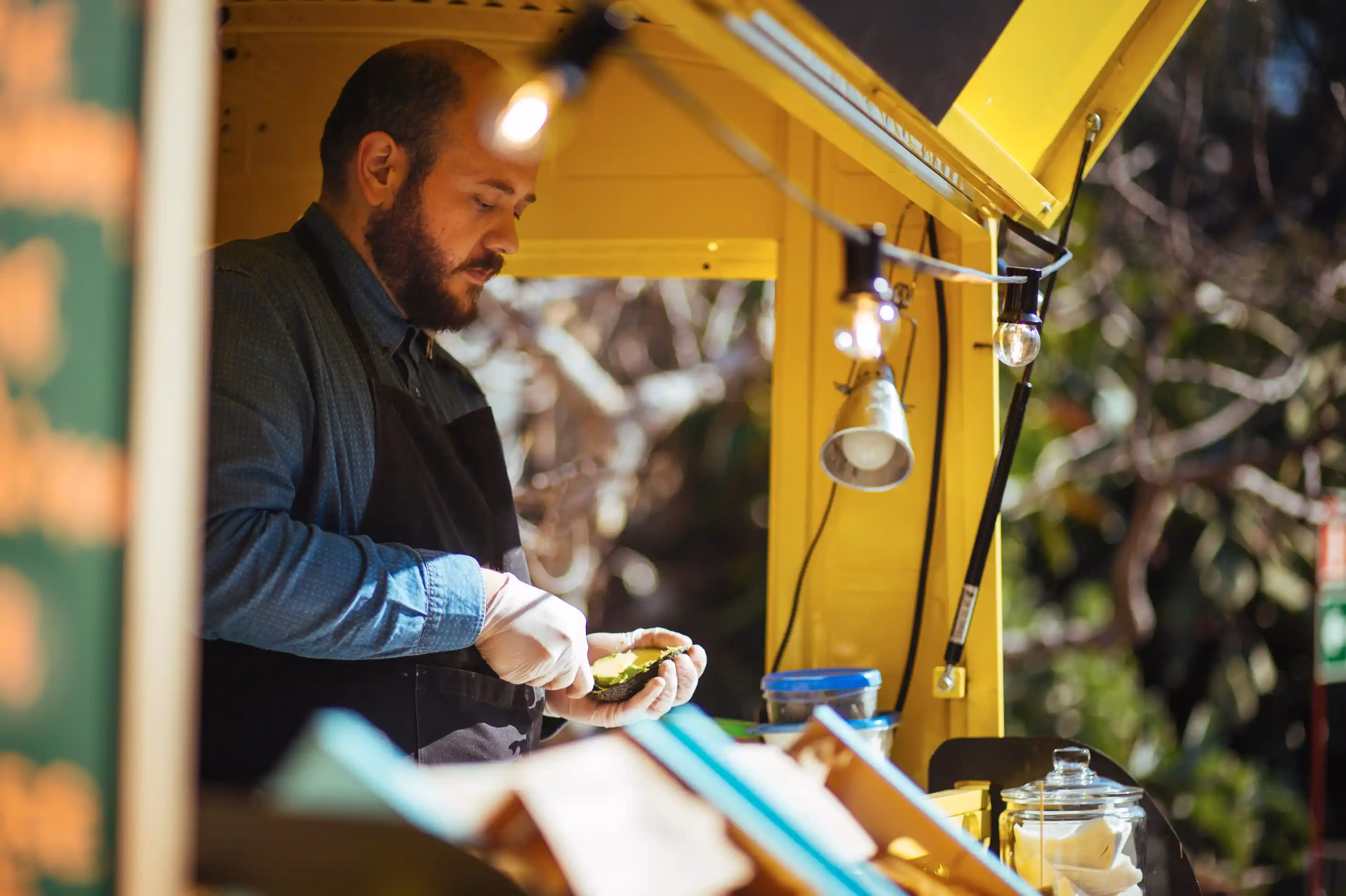 A man in his food truck peeling an avocado