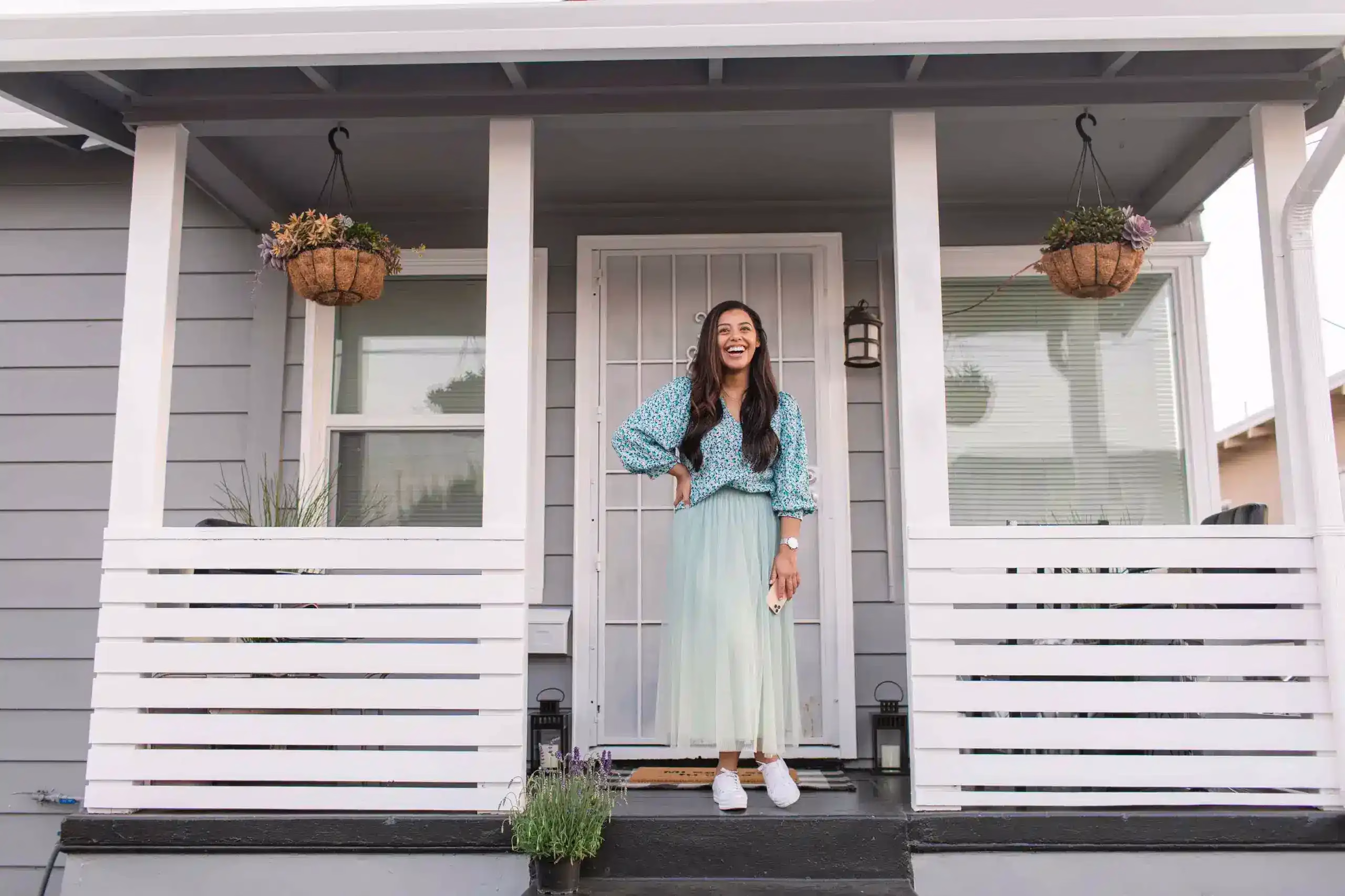 A woman standing on her porch in front of her home with the help of Community Choice Credit Union personal savings