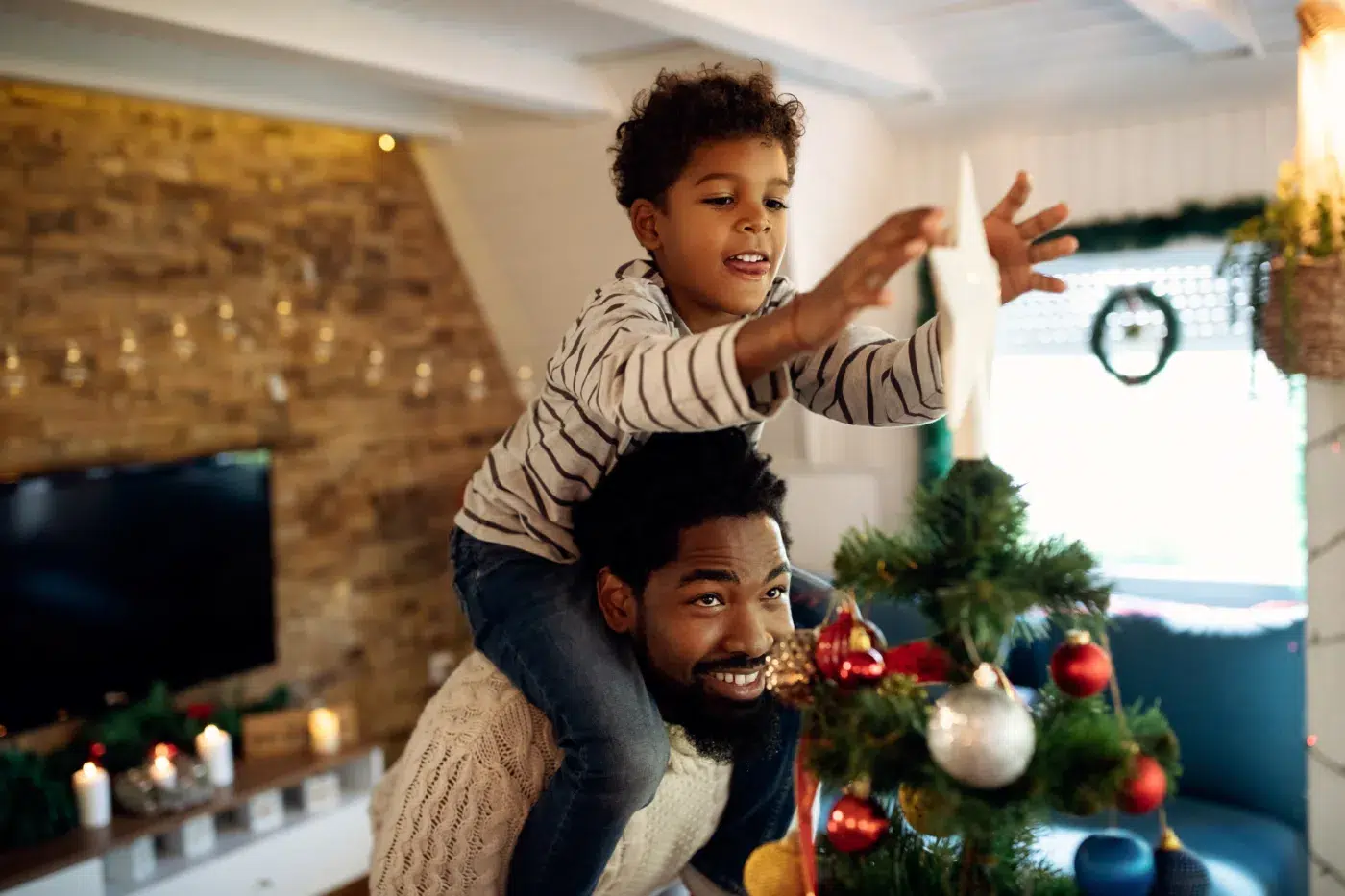 A dad and his son decorate the tree for the holidays.