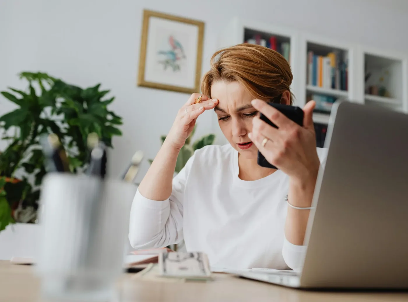 A woman looks at her phone, worried about finances.