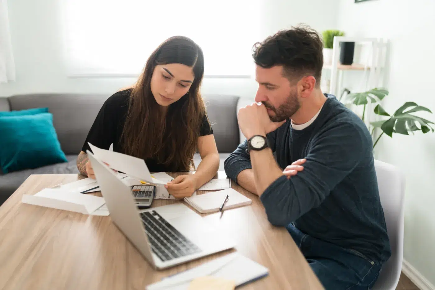 Husband and wife doing their finances with a laptop and bills in their living room. Community Choice Credit Union