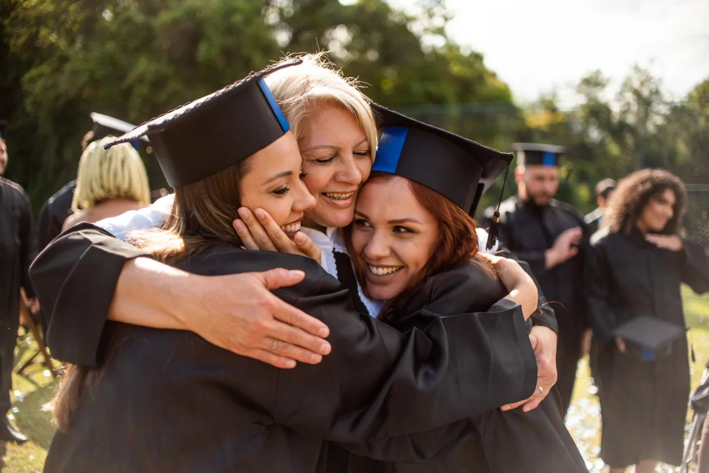 A parent hugs her two graduates