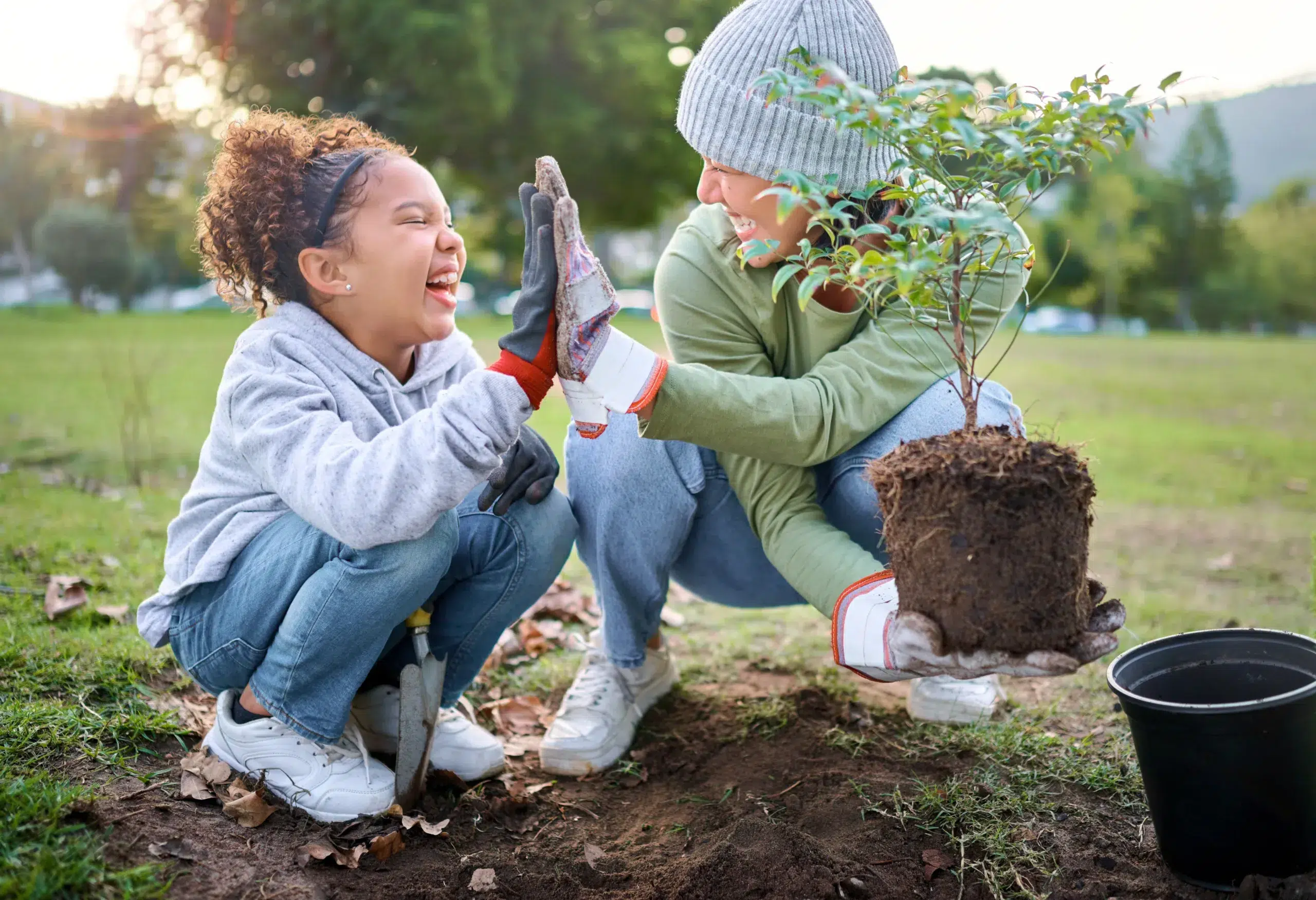 A mother and daughter plant a tree after switching their banking to Community Choice Credit Union in Michigan.