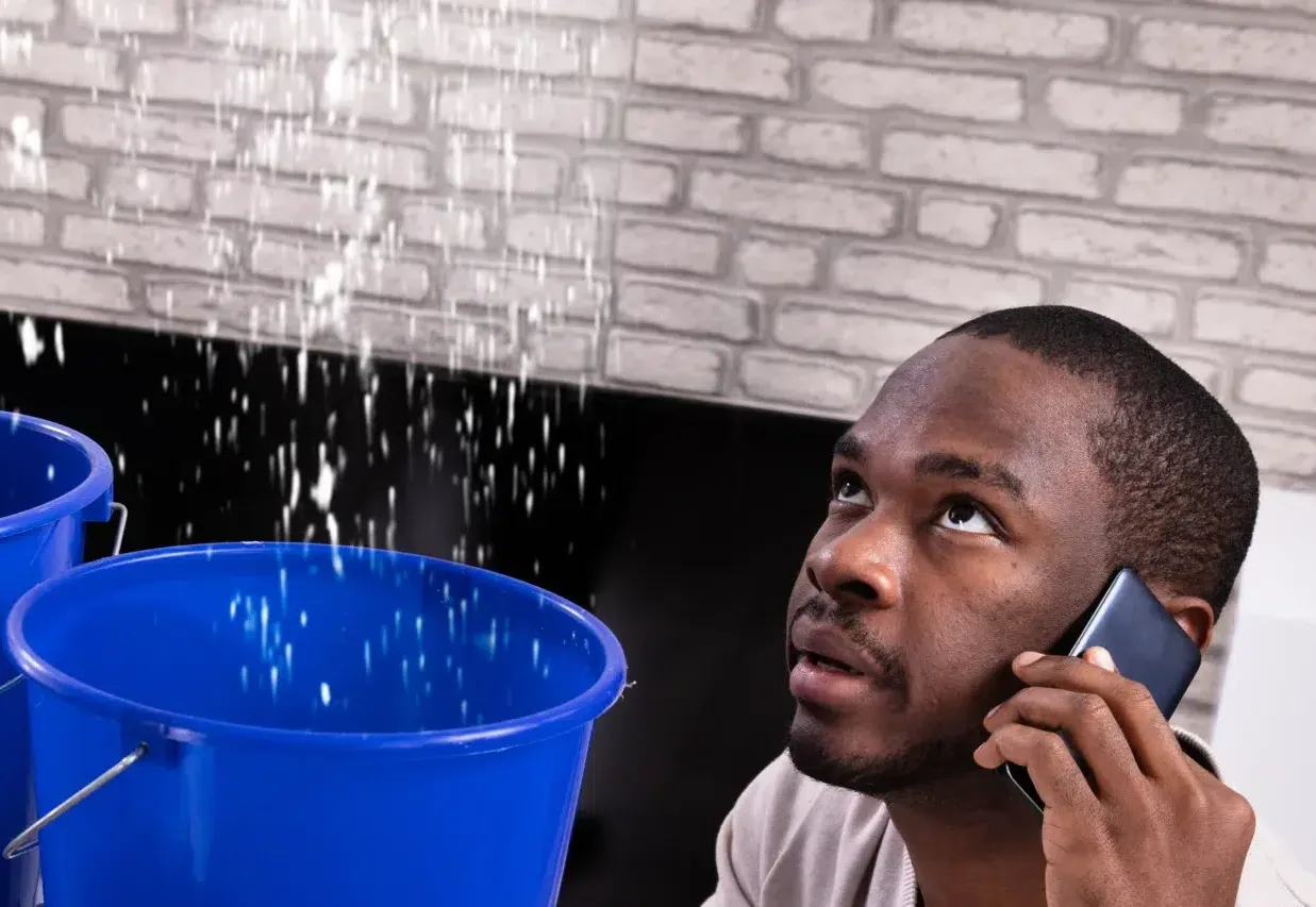 Couple Using Bucket For Collecting Water Leakage From Ceiling And Calling Plumber On Cellphone