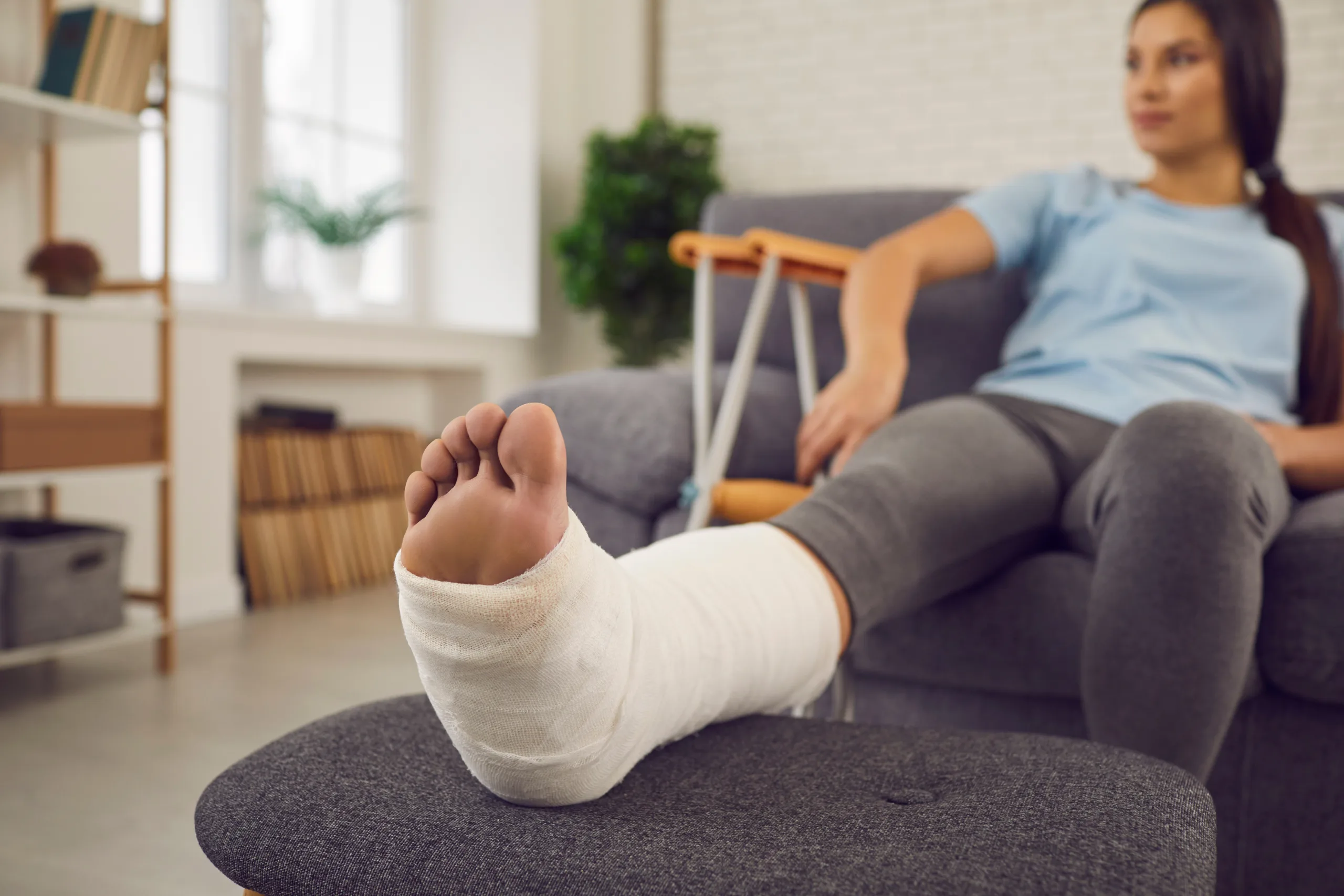 A woman with a broken leg in a cast relaxes on the couch. Community Choice Credit Union